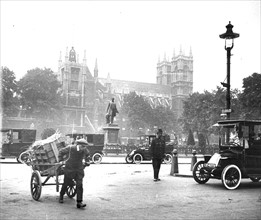 Street scene, Westminster, London, with cars, boy with handcart, and policeman on duty, c 1910.