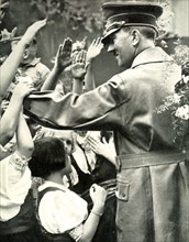 Adolf Hitler greets crowd during a visit to a German town, c1938