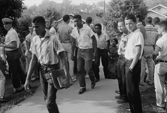 Line of African American boys walking through a crowd of white boys