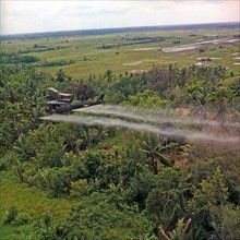 A UH-1D helicopter from the 336th Aviation Company sprays a defoliation agent on a dense jungle area in the Mekong Delta