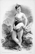 Woman in burlesque costume in front of rocky outcrops c1879