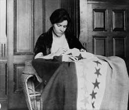 Portrait of Alice Paul, sewing suffrage flag.