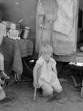 Child of white migrant worker in front of trailer home