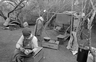 White migrant worker living in camp with two other migrant men. 19390101.
