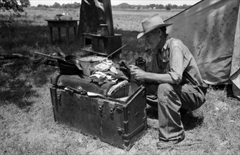 Veteran migrant agricultural worker examining contents of his trunk, Oklahoma