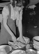 Married daughter of white migrant worker cutting salt meat for dinner. Near Harlingen, Texas 19390101b.