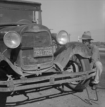 Migrant worker from Oklahoma repairing tire on California highway 1936