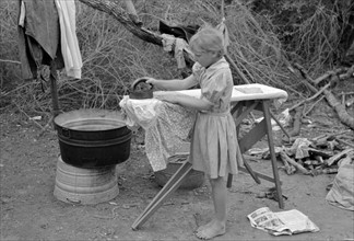 Child of white migrant worker ironing in camp near Harlingen, Texas 19390101.