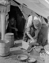 White migrant worker cleaning fish near Mercedes, Texas by Russell Lee, 1903-1986, dated 19390101.
