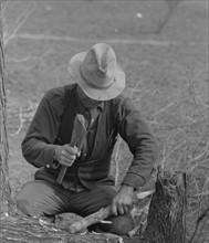 Migrant worker making stakes for the setting up of his tent, 19390101.