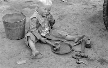 Child of white migrant worker playing with automobile tools near Harlingen, Texas by Russell Lee, 1903-1986, dated 19390101.