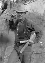 White migrant worker with hatchet and stakes to be used in setting up new camp near Harlingen, Texas by Russell Lee, 1903-1986, dated 19390101.