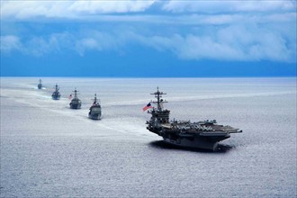 photograph of a the aircraft carrier USS Theodore Roosevelt leading a formation of ships from Carrier Strike Group during a manoeuvring exercise