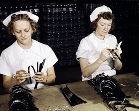 Colour photograph of Navy Wives, Eva Herzberg and Elve Burnham, assembling bands for blood transfusions bottles