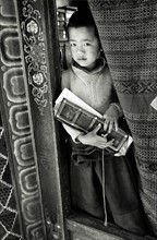 Photograph of a young boy holding a prayer book in Sikkim