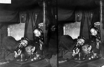 Two Chinese men, on narcotics in opium den.