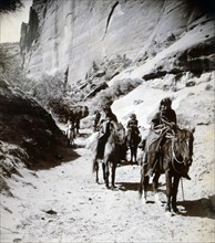 Photograph of a band of mounted Navahos passing through the canon