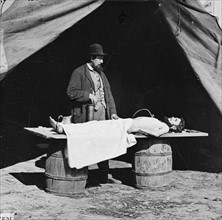 Unknown location. Embalming surgeon at work on soldier's body.