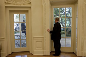 US secret service agent in the oval office, prepares to open a door as President Obama approaches