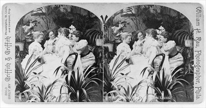 group of women seated at a table, looking at tea leaves 1897