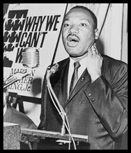 Martin Luther King, Jr. (1929-1968) three-quarter-length portrait, standing, face front, at a press conference.