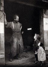 two children talking to a blacksmith standing in the doorway of his forge.