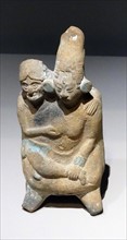 Mayan ceramic figurine of a young woman in the embrace of an old man.