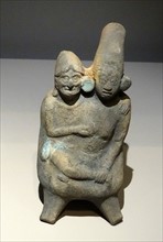 Mayan ceramic figurine of a young woman in the embrace of an old man.