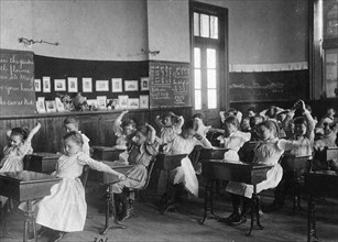 Children doing calisthenics while sitting at their desks