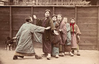 Hand-coloured photograph of Japanese boys playing by Felice Beato
