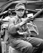 Photograph of a captured German boy soldier enjoying a cup of coffee aboard a U.S. Coast Guard Normandy coast.
