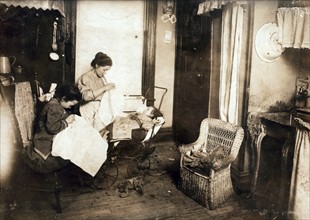 Photograph of women embroidering waists in their dirty kitchen-living room