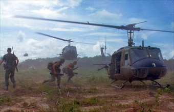 Photograph of American troops running towards a chopper during the Vietnam War