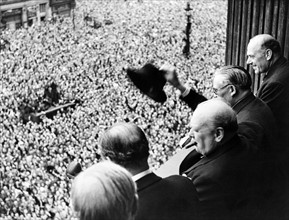 Photograph of Sir Winston Churchill looking out over crowds celebrating the end of the Second World War in London
