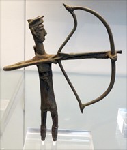 Bronze votive figure of an archer drawing his bow, wearing an horned cap, rectangular breastplate and greaves