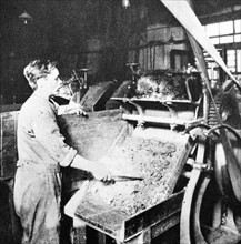 workman sorts ground graphite on a grinding machine