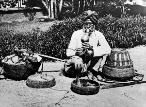 Indian snake charmer with flute luring a cobra from a basket 1925