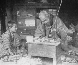 traditional Japanese craftsman watched by his grandson
