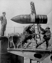 An artillery shell is hoisted into position by soldiers.