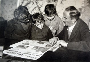 French family read newspaper outlining the liberation of towns in Alsace Lorraine 1944