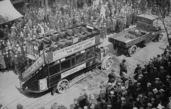 A crowd looks on as an early era London bus,1920