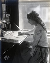 Mary Pickford writing at a desk 1918