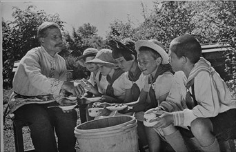 Children on a collective farm tasting honey