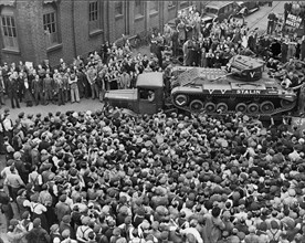 Crowds of people and a guard of honour of tanks
