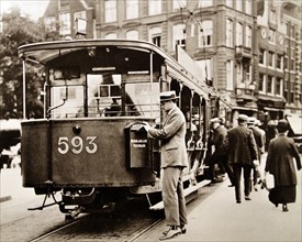 Man posting a letter in a post collection box attached to a tram in Amsterdam