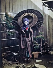 Colour photograph of a Japanese woman with parasol dressed for winter