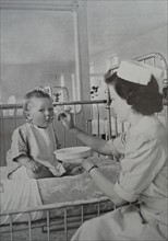 Feeding a baby is one of the many varied duties of the nurse, whose tasks call for skill and patience.