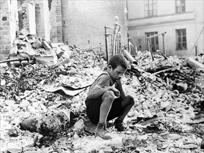 Polish boy sits grieving in the ruins of a street in Warsaw, Poland, September 1939