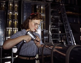 Colour photograph of an female employee operating a hand drill at the North American Aviation Inc.