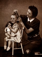 Photograph of a mother brushing hair young daughter's hair